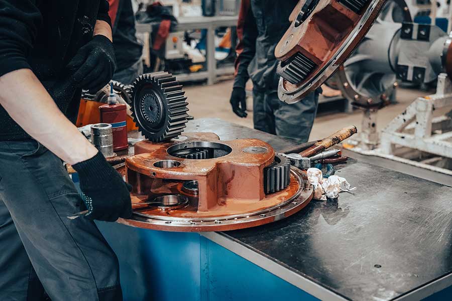 Production engineering technician repairing a gear drive in a factory