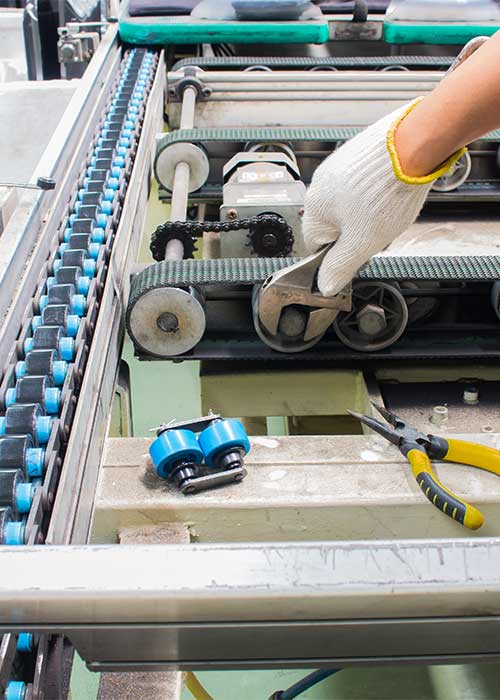 Breakdown service engineer repairing a broken conveyor belt in a factory